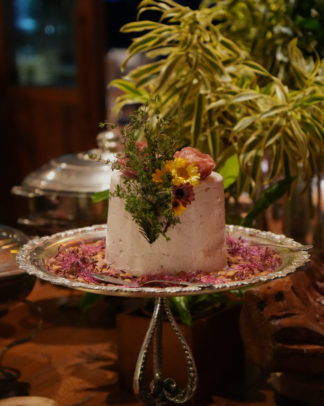Prato montado com ervas e flores sobre travessa prateada em um buffet